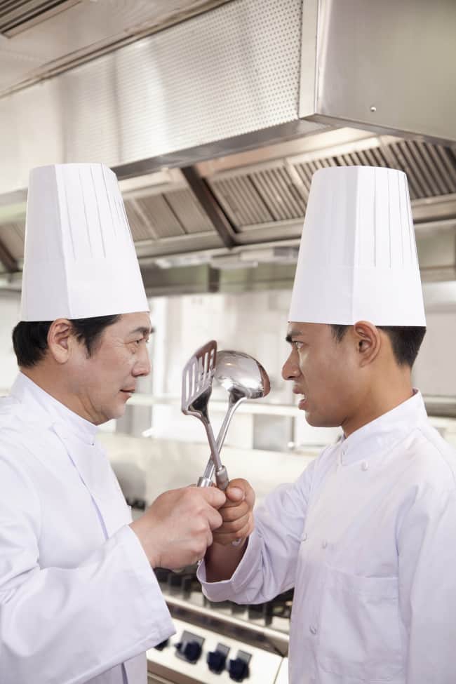 Chefs with crossed cooking utensils prepared for battle