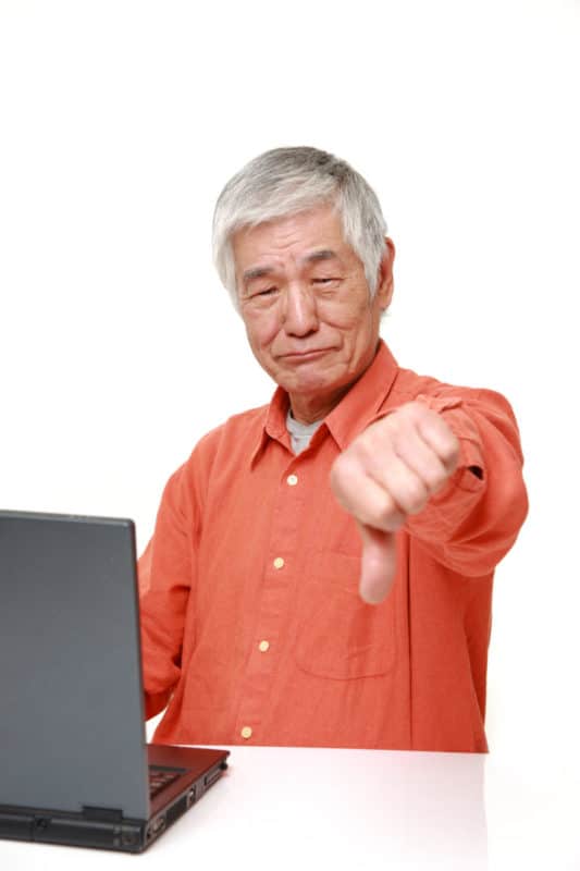 Older man using laptop looks disappointed
