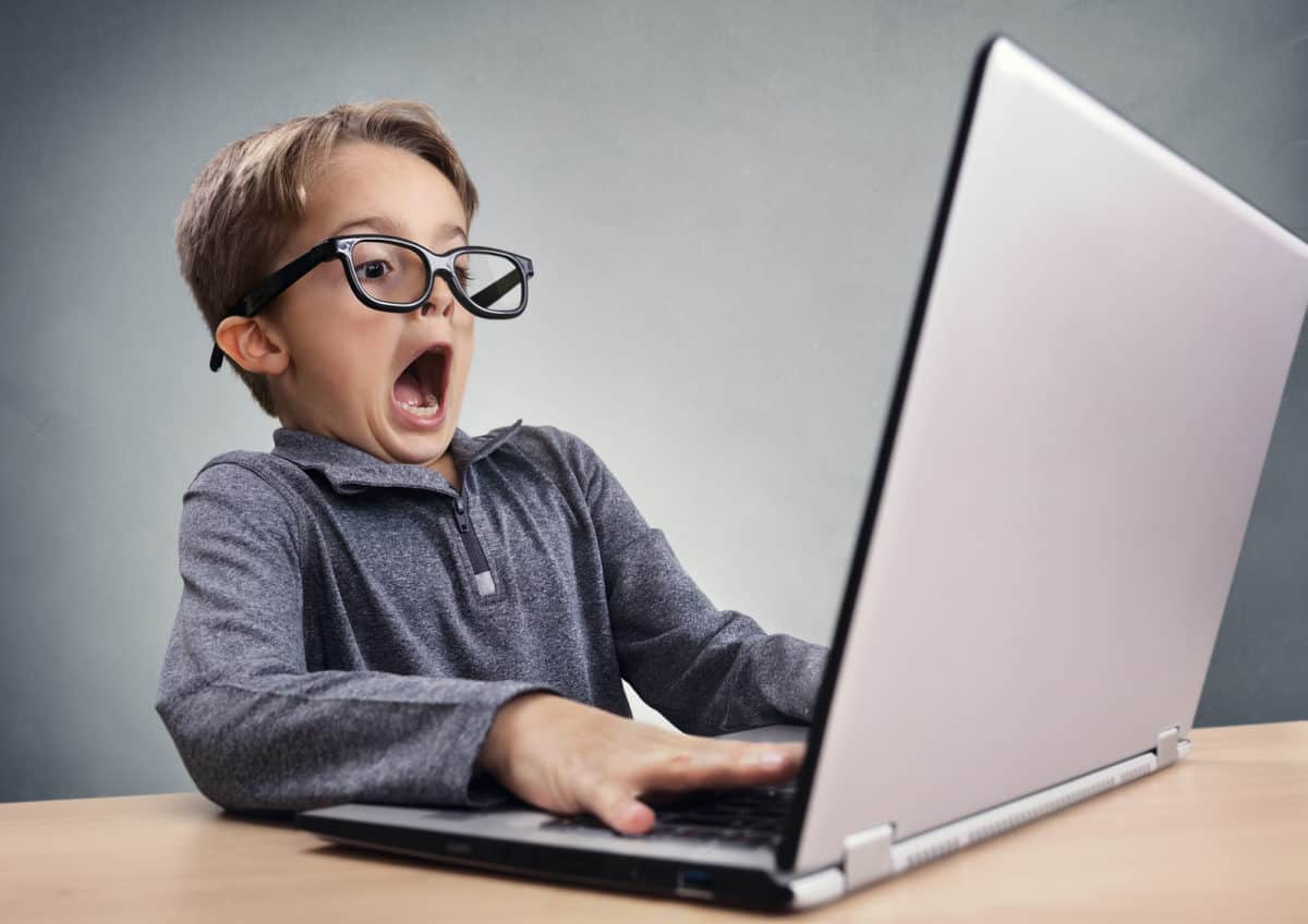 Boy with glasses using laptop quite surprised